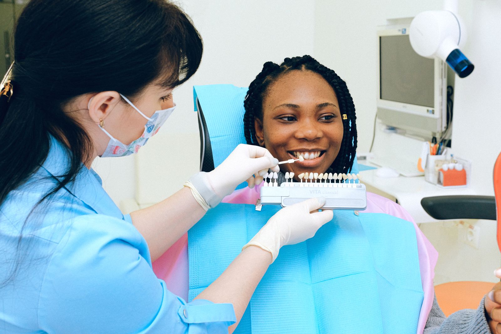 Clinician matching a shade guide with a smiling patient